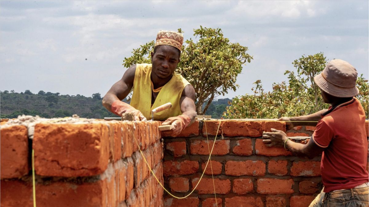 Two men building a brick wall in a climate project region